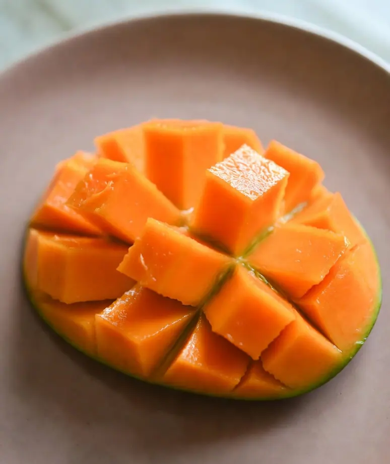 Correctly prepared safe mango serving — small pea-sized pieces of peeled, pitted ripe mango flesh